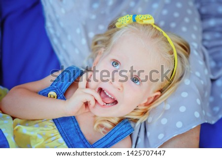 Little girl blonde builds faces lying on mother's feet / copy space
