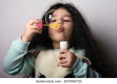 Little Girl Blowing Air In To A Plastic Bubble Maker, Creating A Big Transparent Bubble.