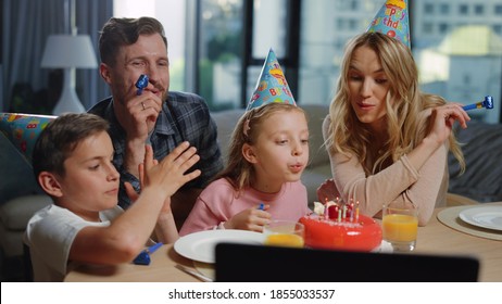 Little Girl Blowing Candles On Cake With Relatives At Home Party. Cheerful Parents Kids Celebrating Birthday Online Indoors. Portrait Of Smiling Family Having Fun In Front Of Computer In Living Room.