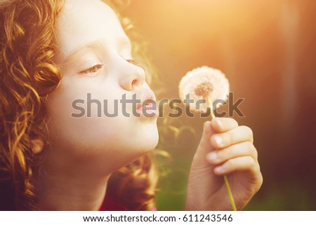 Little girl blowing dandelion.