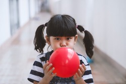 Little Girl Blowing Up Red Balloons Happy And Funny At Home