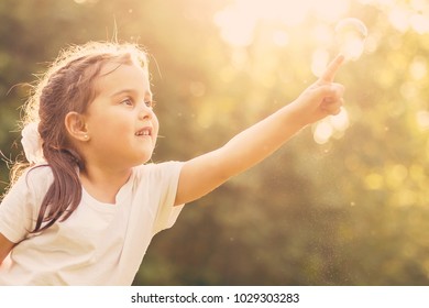 little girl blowing soap bubbles with her grandmother outdoors