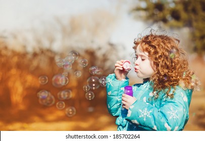 Ein kleines Mädchen bläst Seifenblasen, Nahaufnahme-Porträt. Toning-Foto.