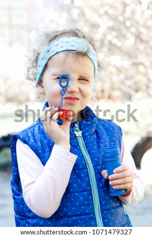 A little girl is blowing soap bubbles.