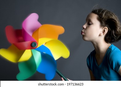 A Little Girl Blowing A Very Big Pin Wheel.