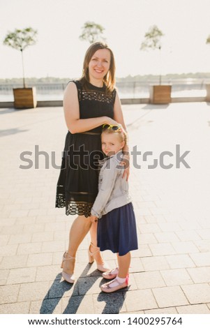 little girl in a blue dress having fun with her mother