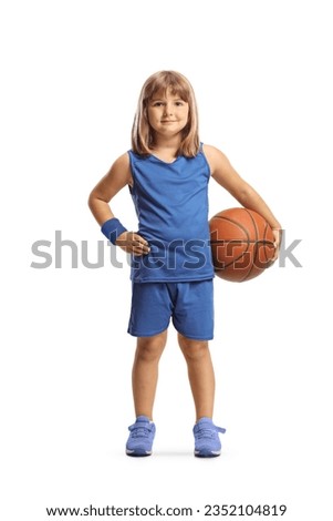 Little girl in a blue jersey kit holding a basketball and smiling isolated on white background