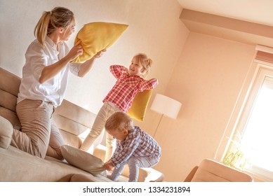 Little Girl And Boy Having Funny Pillow Fight With Their Mom And Enjoying Free Time At Home