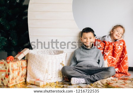 Little girl and boy sitting on the background of the moon and the baskets decorated under the new Year