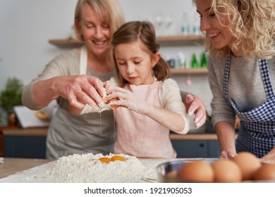 Little girl breaks an egg into the flour                                - Powered by Shutterstock