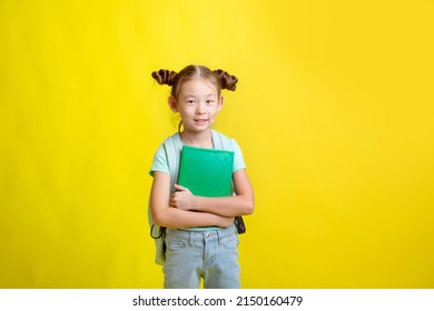 a little girl with a briefcase holds a book isolated on a yellow background