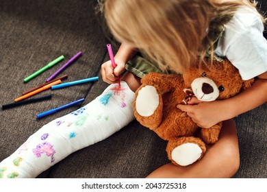 Little Girl With A Broken Leg On The Couch. The Child Draws With Felt-tip Pens On A Plaster Bandage.