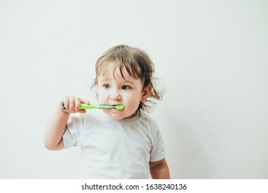 Little girl brushes her teeth with a toothbrush on a light background cute