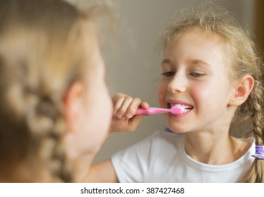 Little girl brushing her teeth with toothbrush.