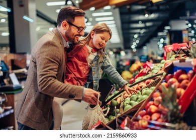 Little girl is buying groceries in the supermarket with her father. He carrying her and picking together fresh fruits - Powered by Shutterstock