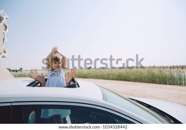 Little girl in the car\
waving near lake