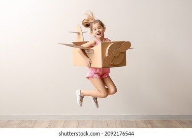 Little girl with cardboard airplane jumping near light wall - Powered by Shutterstock