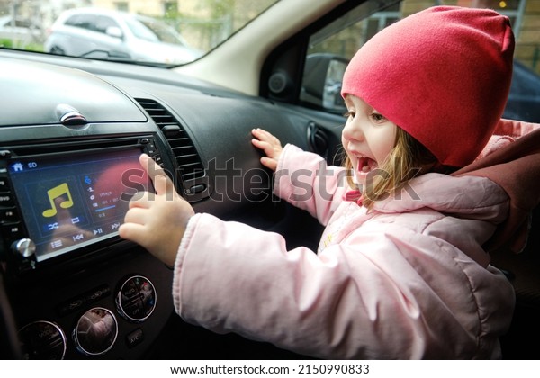A little\
girl Changing Radio Station While Listening Music In Car. Listening\
to the radio in the car. Auto\
music