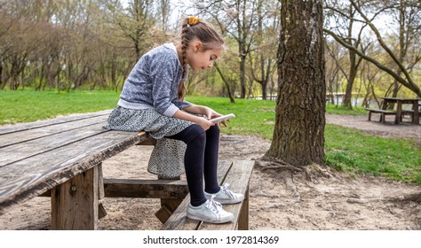 A Little Girl Checks Her Phone, Not Paying Attention To The Beautiful Nature Around.