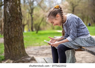 A Little Girl Checks Her Phone, Not Paying Attention To The Beautiful Nature Around.