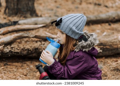 Little girl, child drinks hot tea, water from a thermos to keep warm outdoors in autumn. Photography, portrait. - Powered by Shutterstock