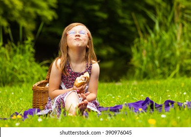 Little Girl Child Eating Sandwich Hot Dog On Picnic. Summer Vacation Leisure. Happy Kid Relaxing In Park Meadow. 