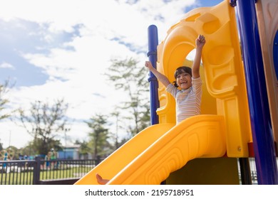 Little Girl Child Going Down The Slide Outdoors At The Park Or Playground