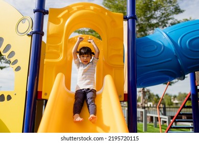 Little Girl Child Going Down The Slide Outdoors At The Park Or Playground