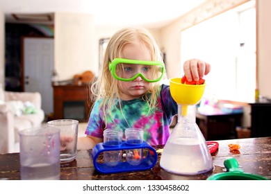 A Little Girl Child Is At Home Doing A Science Experiment With A Toy Science Kit.