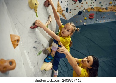 Little girl, child practicing bouldering, training with instructor. Little girl climbing wall, indoor class. Concept of bouldering, sport climbing, hobby, active lifestyle, school, training course - Powered by Shutterstock