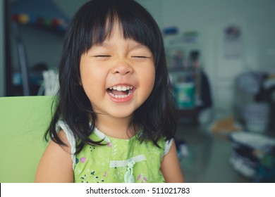 Little girl child showing front teeth with big smile: Healthy happy funny smiling face young adorable lovely female kid with new tooth dental loss: Joyful portrait of asian elementary school student
