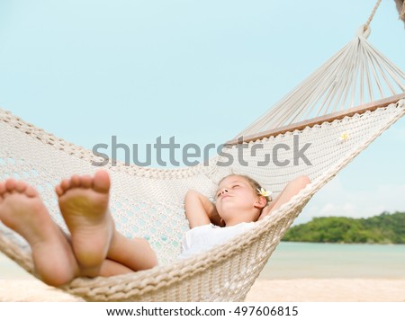 little girl child swinging in hammock on the beach eyes closed sea ocean