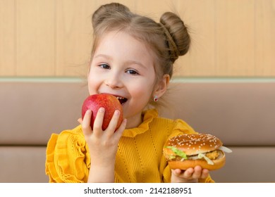 Little Girl With Choice Of Apple And Burger. Healthy Vs Unhealthy Snack For Kid. Child With Fast Food And Fruit. Healthy Eating Concept