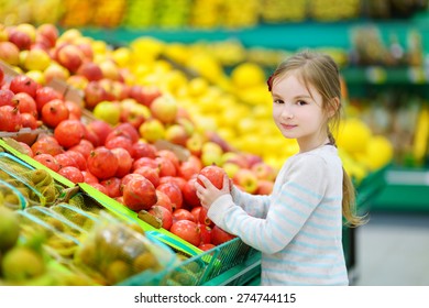 Little girl choosing pomegranates in a food store or a supermarket