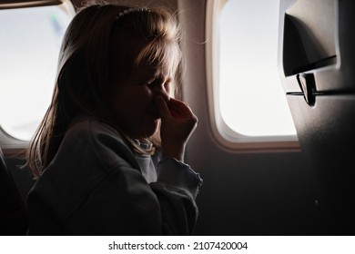 A Little Girl Clamps The Nose Because Of The Unpleasant Smell In An Airplane Seat By The Window. Flights With Children In Economy Class. The Smell Of Sweat, Fumes And Dirty Feet From Passengers 