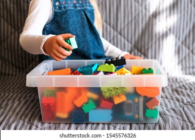 Little Girl Cleaning Up The Toy Box At Home. Child's Space Organization.