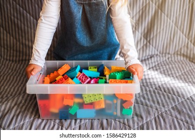 Little Girl Cleaning Up The Toy Box At Home. Child's Space Organization.