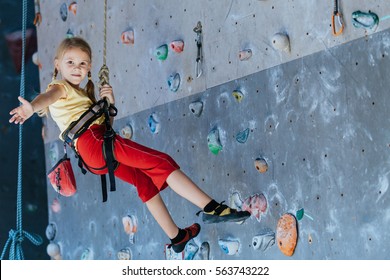 little girl climbing a rock wall indoor. Concept of sport life.