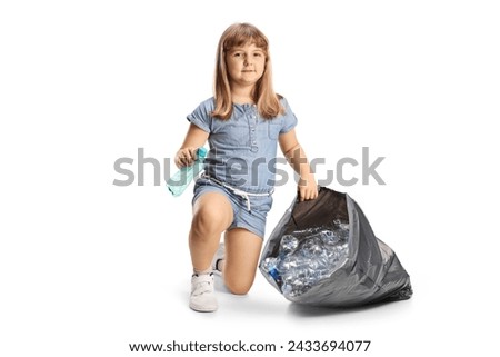 Little girl collecting plastic bottles in a bag and smiling at camera isolated on white background