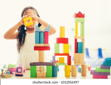 Little Girl In A Colorful Shirt Playing With Construction Toy Blocks Building A Tower . Kids Playing. Children At Day Care. Child And Toys.
