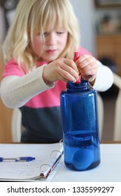 Little Girl Conducting A Science Experiment At Home With Eggs, Vinegar And Highlighter Ink To Make Glowing Bouncy Eggs