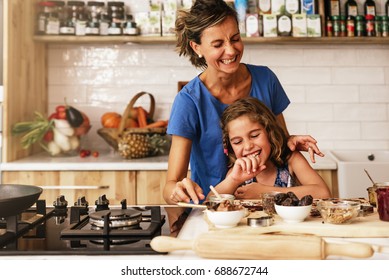 Kleines Mädchen kocht mit ihrer Mutter in der Küche. Kinderkochkonzept.