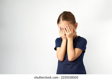 Little girl covering her eyes with her hands. Portrait of a girl cover her face, white background with copy space