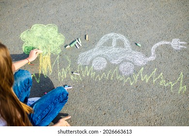 Little Girl With Creative Craft Hobby Drawing Electro On The Asphalt With Chalk Car Environment, Eco Friendly, Save Energy In Park At Summer Day