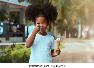 Little girl with curly hair, fluffy, delicious ice cream : Portrait 5-year-old, half-Asian, African girl walks eating ice cream in a garden and enjoys hand-melted milk cream on a hot day in Thailand. - Powered by Shutterstock