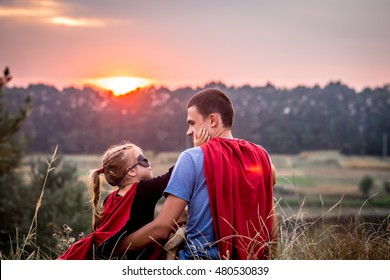 little girl with dad dressed in super heroes, happy loving family, father and daughter playing outdoors, family values