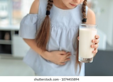 Little Girl With Dairy Allergy Holding Glass Of Milk Indoors