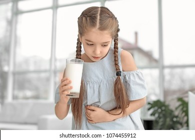 Little Girl With Dairy Allergy Holding Glass Of Milk Indoors