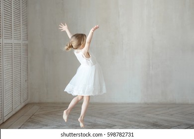A little girl dancing in a room in a beautiful dress
