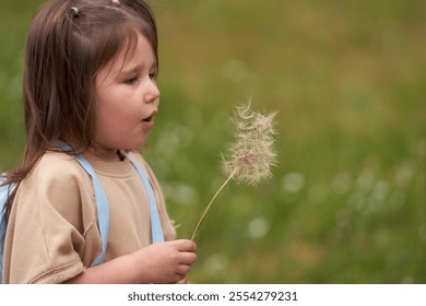 A little girl with a dandelion on a long stem in her hand. Close-up portrait on blurred background of green meadow. Copy space.                         - Powered by Shutterstock